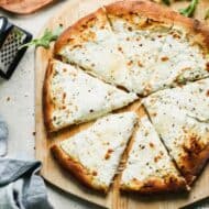 White pizza cut into slices, on a pizza peel.