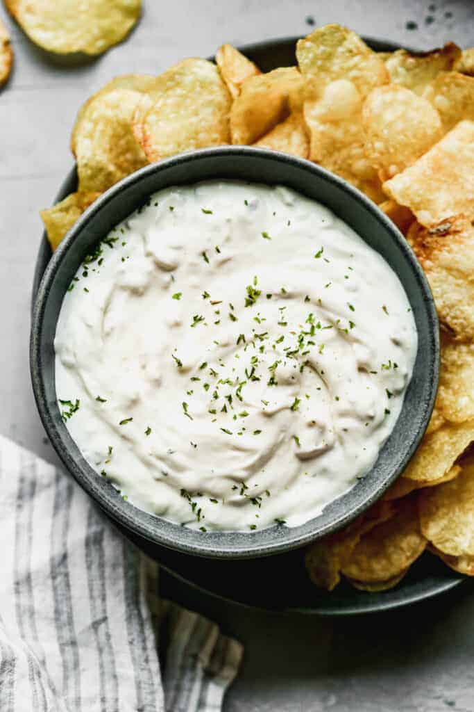 Homemade Clam Dip in a bowl with potato chips around it.