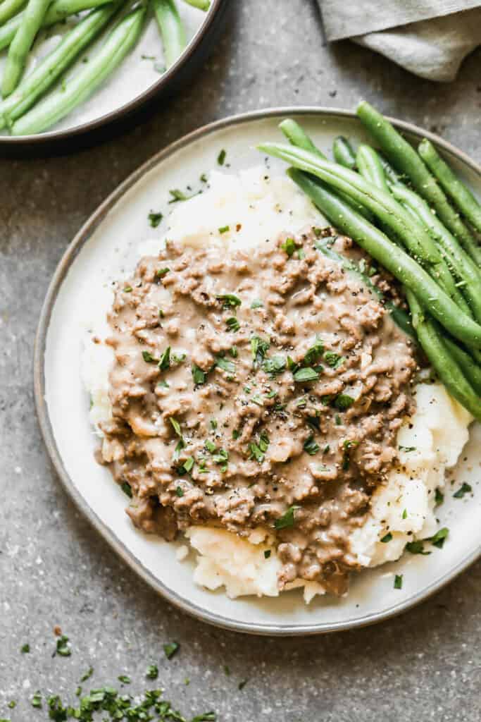 Hamburger Gravy served over mashed potatoes with green beans on the side.