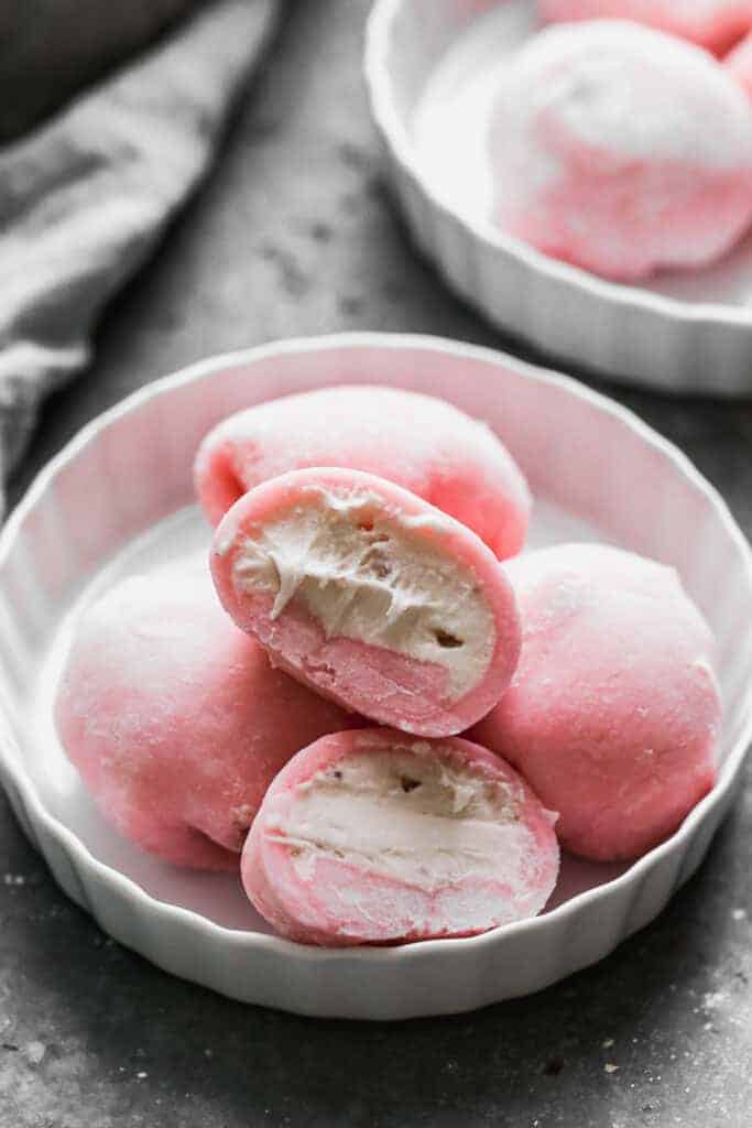 Four Mochi Ice Cream balls on a plate with one cut in half to show the ice cream center.