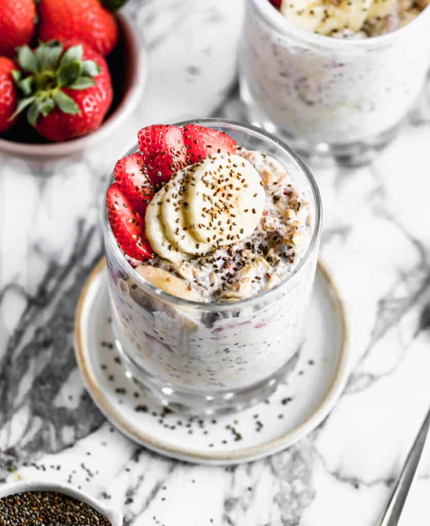 Easy Strawberry Overnight Oats in a glass cup topped with chopped strawberries, sliced bananas, and a sprinkle of chia seeds.