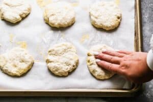 Une main façonnant la pâte pour les muffins anglais en disques.