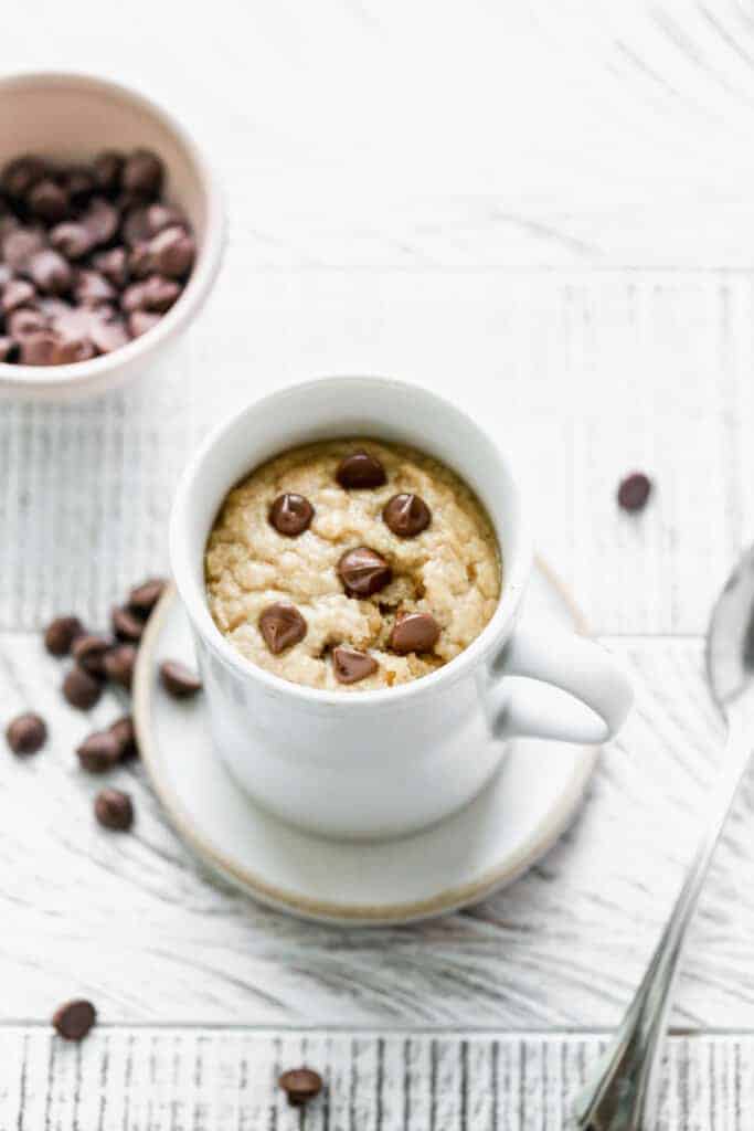 Peanut Butter cake cooked in a white mug, with chocolate chips on top.