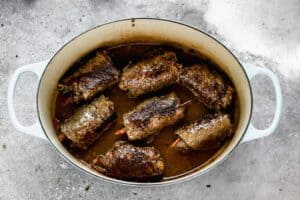 A pot with German Rouladen beef rolls cooking in a gravy that was made from the cooked beef juices.