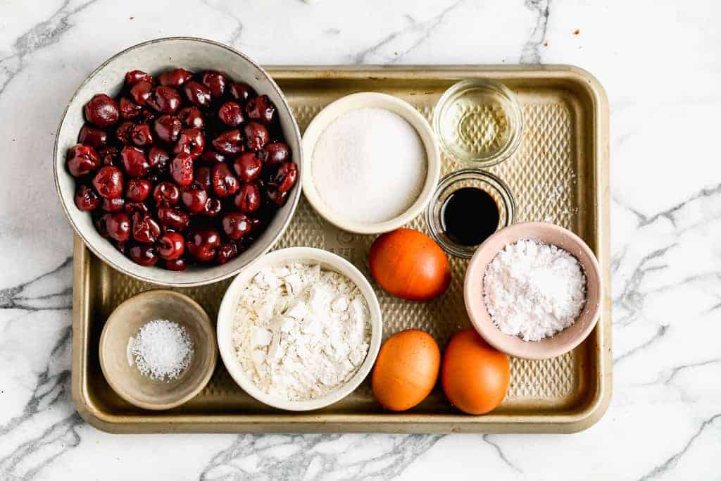The ingredients for Cherry Clafoutis, including egg, flour, vanilla, cherries, sugar and salt.