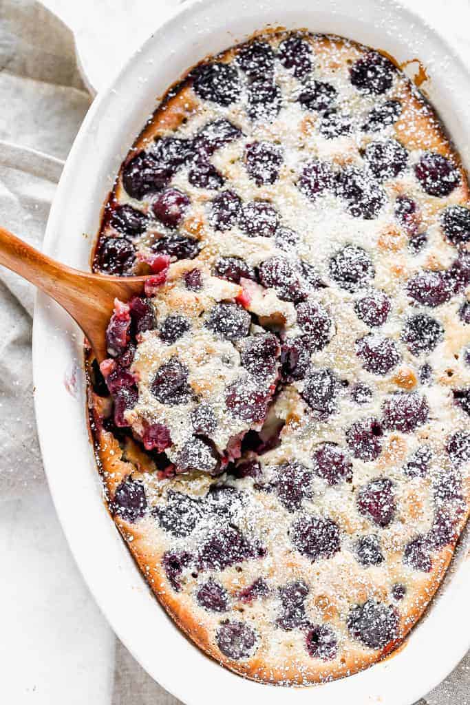 Cherry Clafoutis baked in an oval dish, dusted with powdered sugar