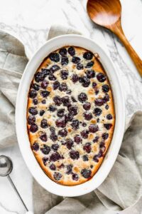 Baked Cherry Clafouti in a white dish, with a serving spoon on the side.