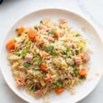 Ham fried rice with peas, carrots and ham, served on a white plate.
