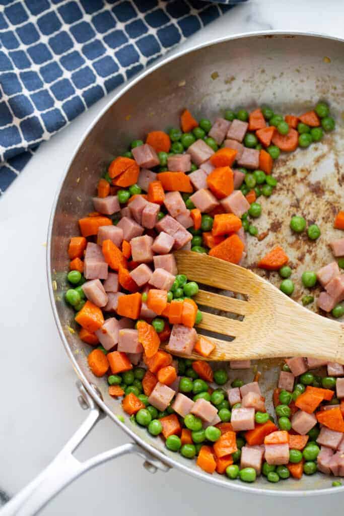 Peas, carrots and chopped ham in a skillet.