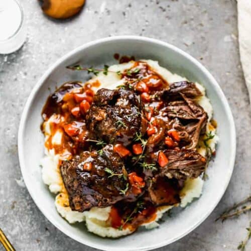 Instant pot short ribs served over mashed potatoes, on a plate.