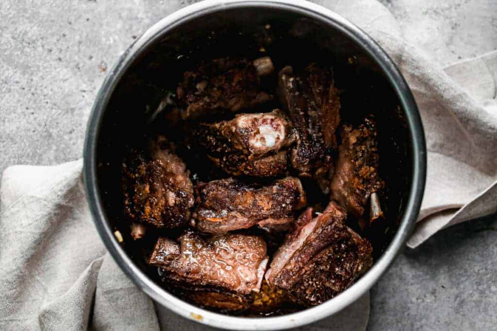 Beef short ribs searing in an instant pot.