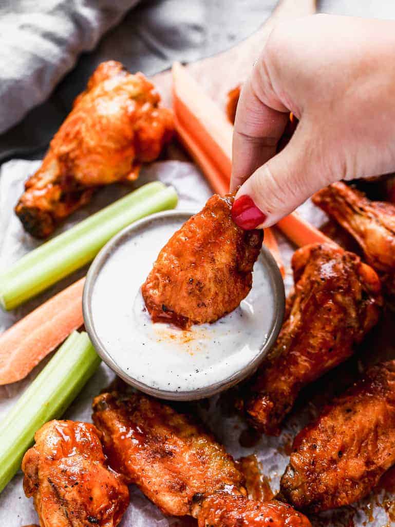 A chicken wing being dipped in ranch.