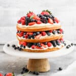A fresh Berry Cake recipe with three tiers of yellow cake, topped with lemon mousse, and fresh berries.