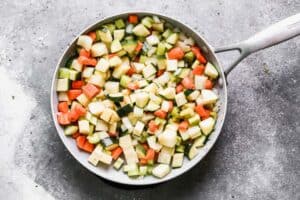 Chopped carrot, potato, celery, onion and zucchini sautéing in a skillet.