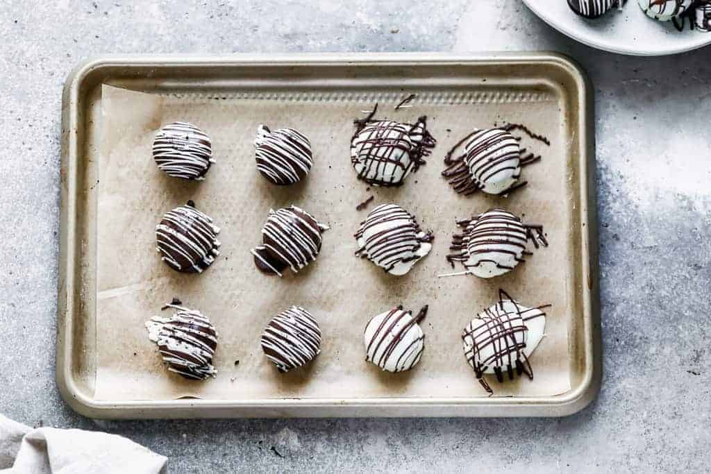 Oreo balls dipped in chocolate, on a sheet pan to set up.