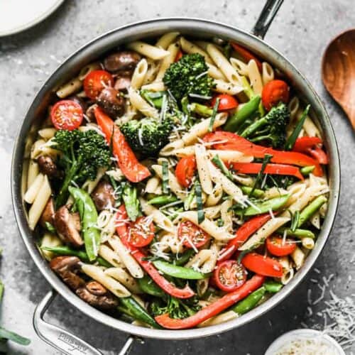 Pasta Primavera made with penne pasta and sautéed vegetables, cooking in a large skillet.