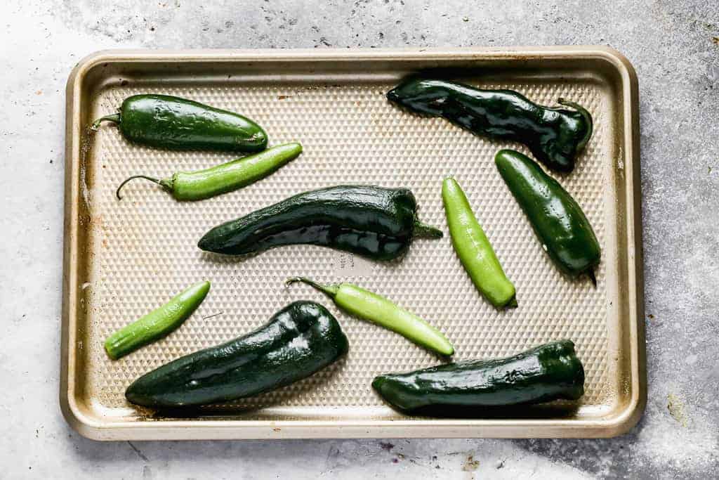 Serrano and jalapeño peppers on a baking tray, ready to be roasted.