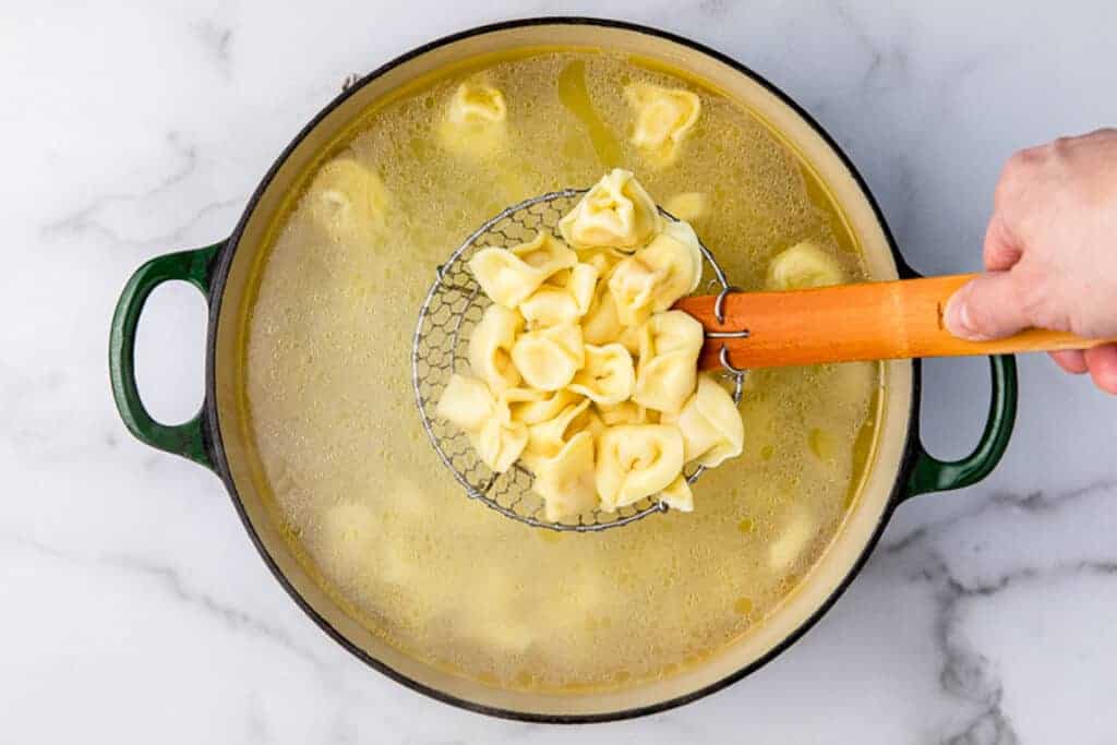 Tortellini cooking in a pot of boiling water.
