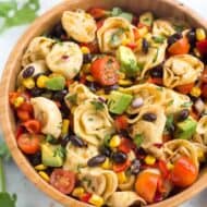 A bowl of Tortellini Pasta Salad with beans, corn, avocado and dressing.