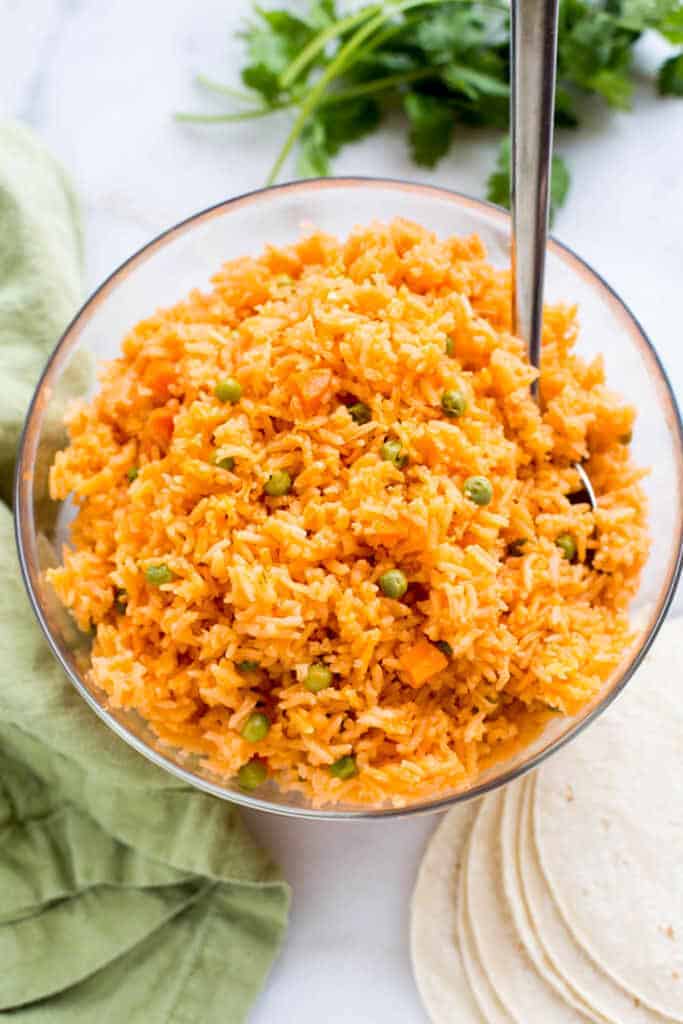 Mexican Rice with peas and carrots, served in a large bowl, with a spoon.