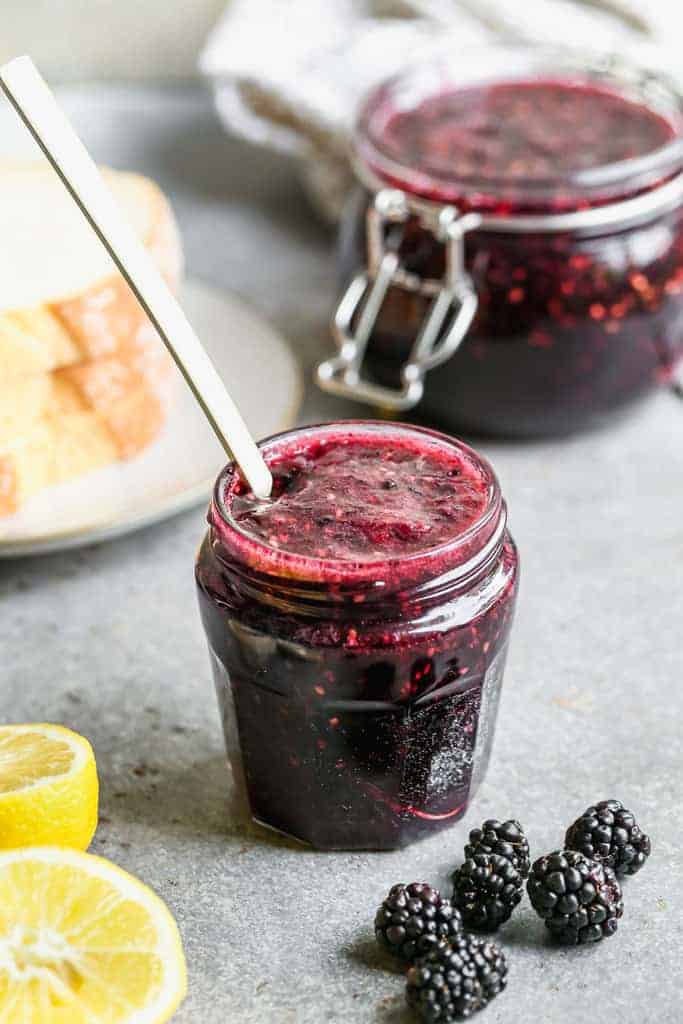 A jar of homemade Blackberry jam, with a small spoon resting inside.