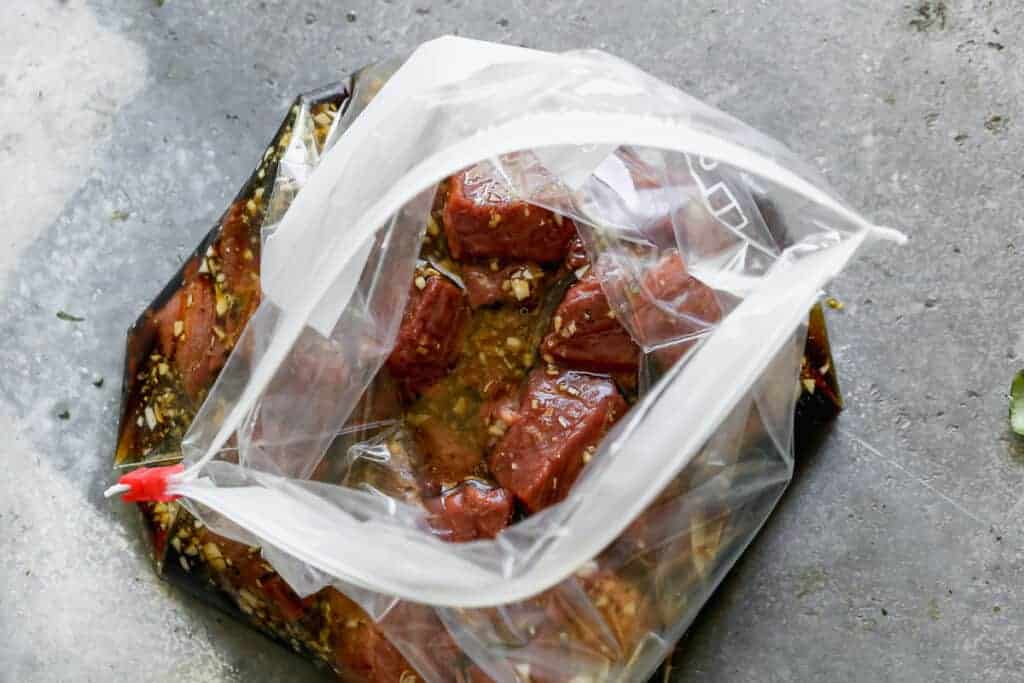 Chunks of steak added to a ziploc bag with steak kabob marinade.