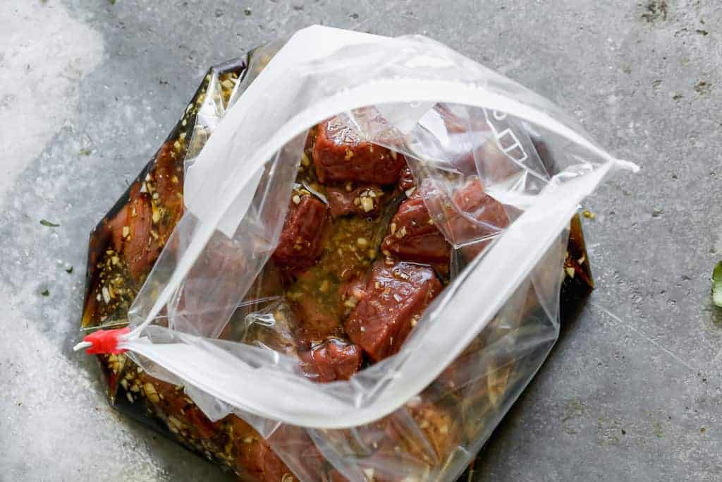 Des morceaux de steak ajoutés à un sac ziploc avec une marinade de brochette de steak.