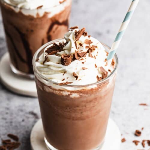 A serendipity Frozen Hot Chocolate recipe in a glass topped with whipped cream and chocolate shavings.
