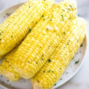 Easy Instant Pot Corn on the Cob brushed with butter and sprinkled with parsley, ready to serve.