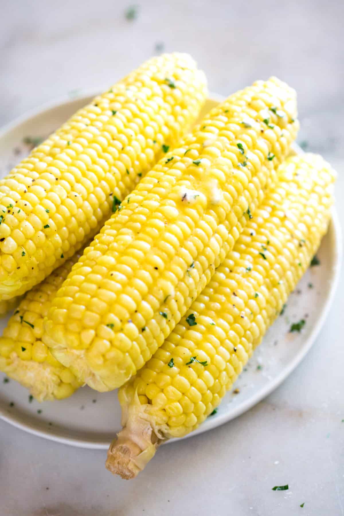 Easy Instant Pot Corn on the Cob brushed with butter and sprinkled with parsley, ready to serve.