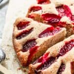A baked plum cake with a slice cut from it.
