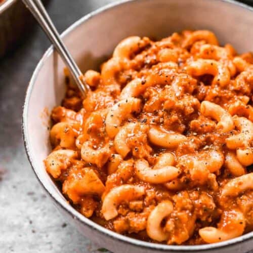 A bowl full of American Goulash made with macaroni noodles, sauce and ground beef.