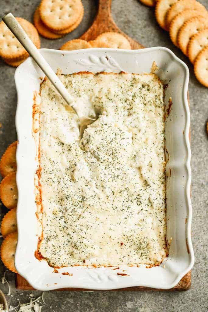 Artichoke Dip served in a baking dish, with a spoon.