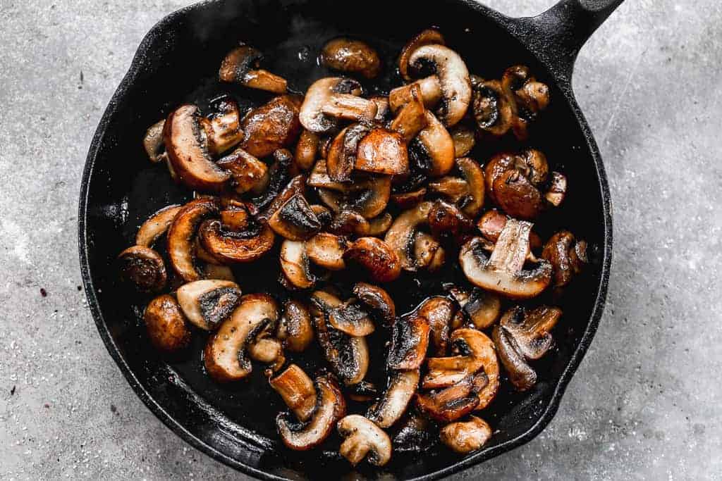 Sauteéd mushrooms deglazed in a cast iron skillet, and ready to eat.