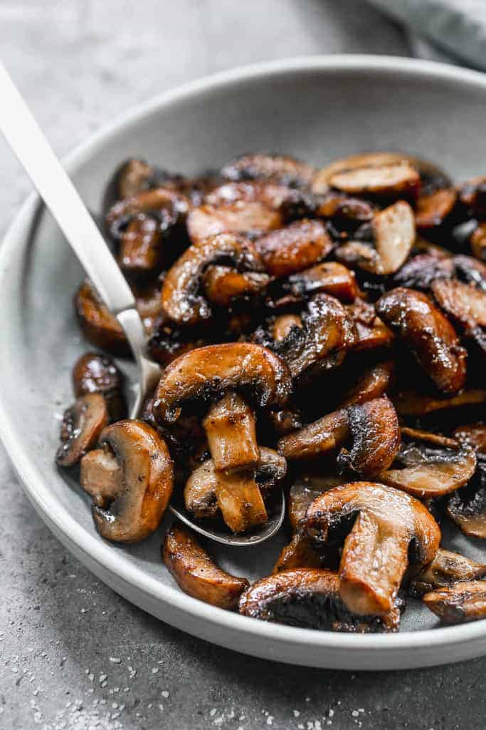 A plate of sauteed mushrooms with a spoon.