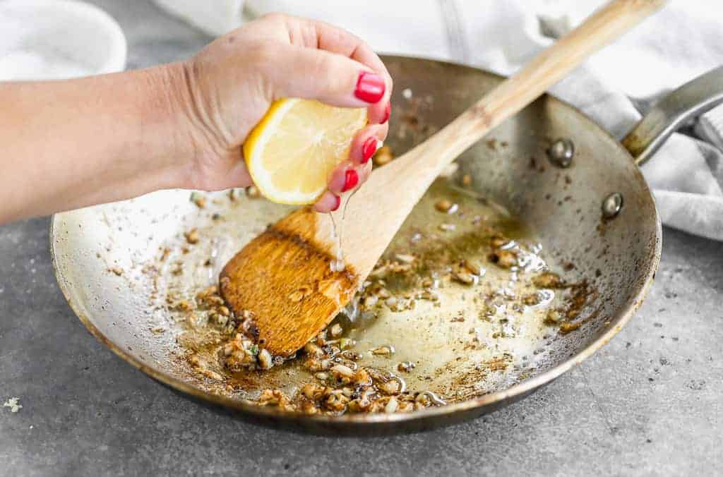 Jus de citron frais pressé sur une poêle pour faire une sauce pour pétoncles scellés.