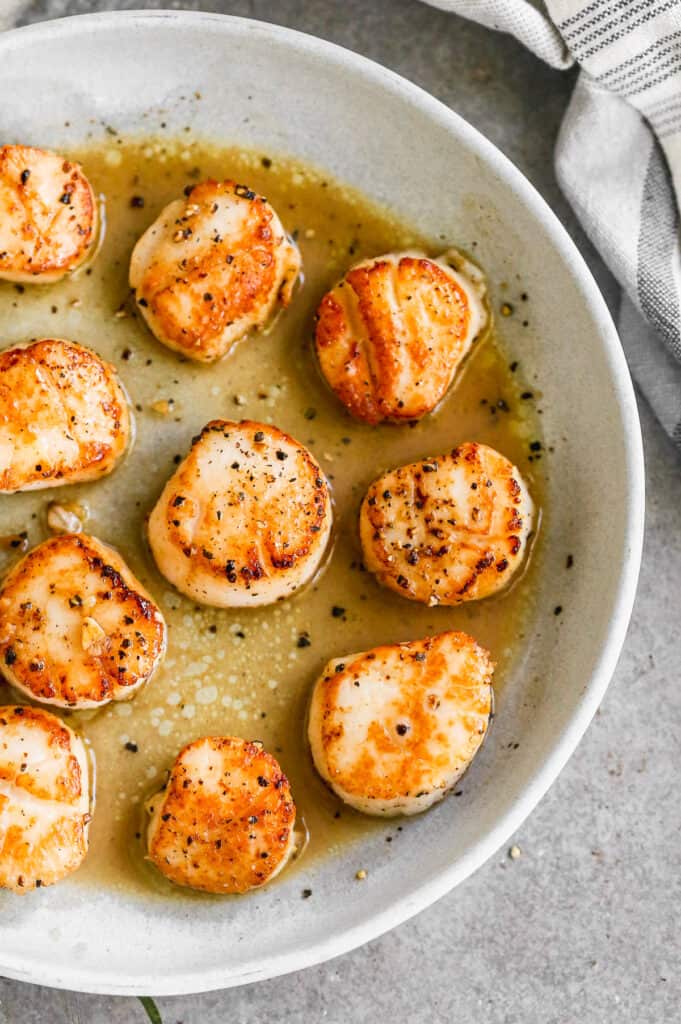 Seared scallops in garlic butter sauce, served on a plate.