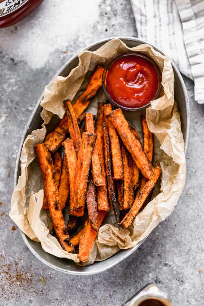 Air Fryer Sweet Potato Fries served in a basket with ketchup for dipping.