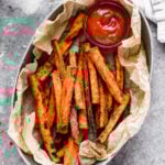 A basket of crispy Air Fryer Sweet Potato Fries served with a side of ketchup for dipping.