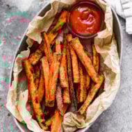 A basket of crispy Air Fryer Sweet Potato Fries served with a side of ketchup for dipping.