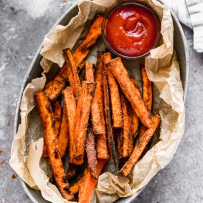 A basket of crispy Air Fryer Sweet Potato Fries served with a side of ketchup for dipping.
