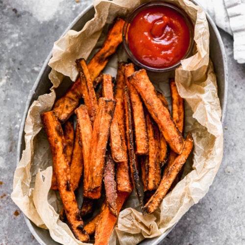 A basket of crispy Air Fryer Sweet Potato Fries served with a side of ketchup for dipping.
