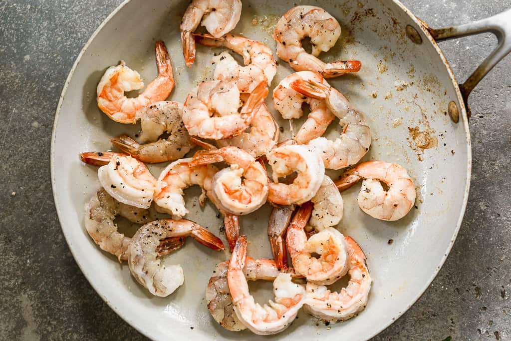 Shrimp cooking in a hot skillet with oil.
