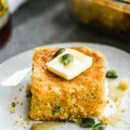 A slice of jalapeño cornbread on a plate, with a little butter on top.