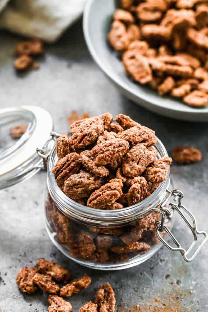 A jar of the best Candied Pecans recipe with a sweet cinnamon sugar coating.
