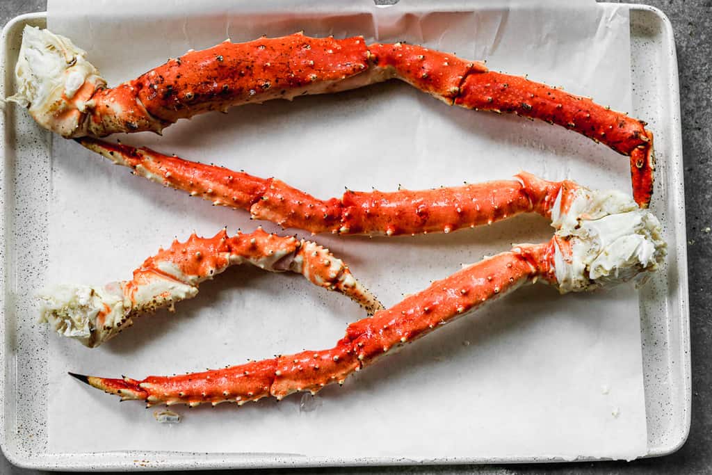 King crab legs on a baking sheet lined with parchment paper.