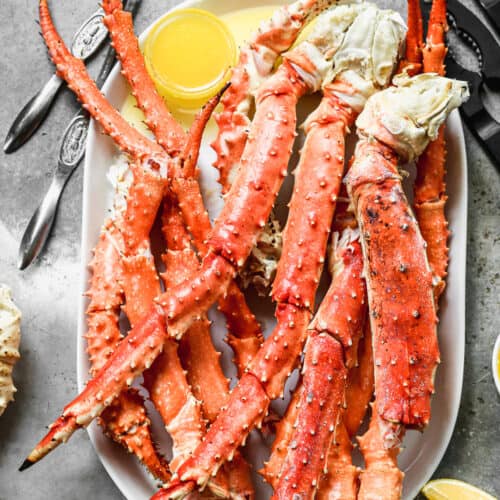 King Crab Legs on a serving platter with melted butter in a small bowl for serving.