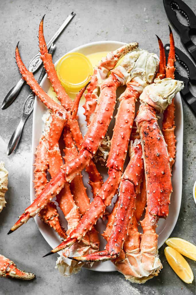 King Crab Legs on a serving platter with melted butter in a small bowl for serving.