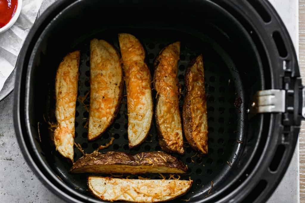 Potato wedges in the basket of an air fryer.