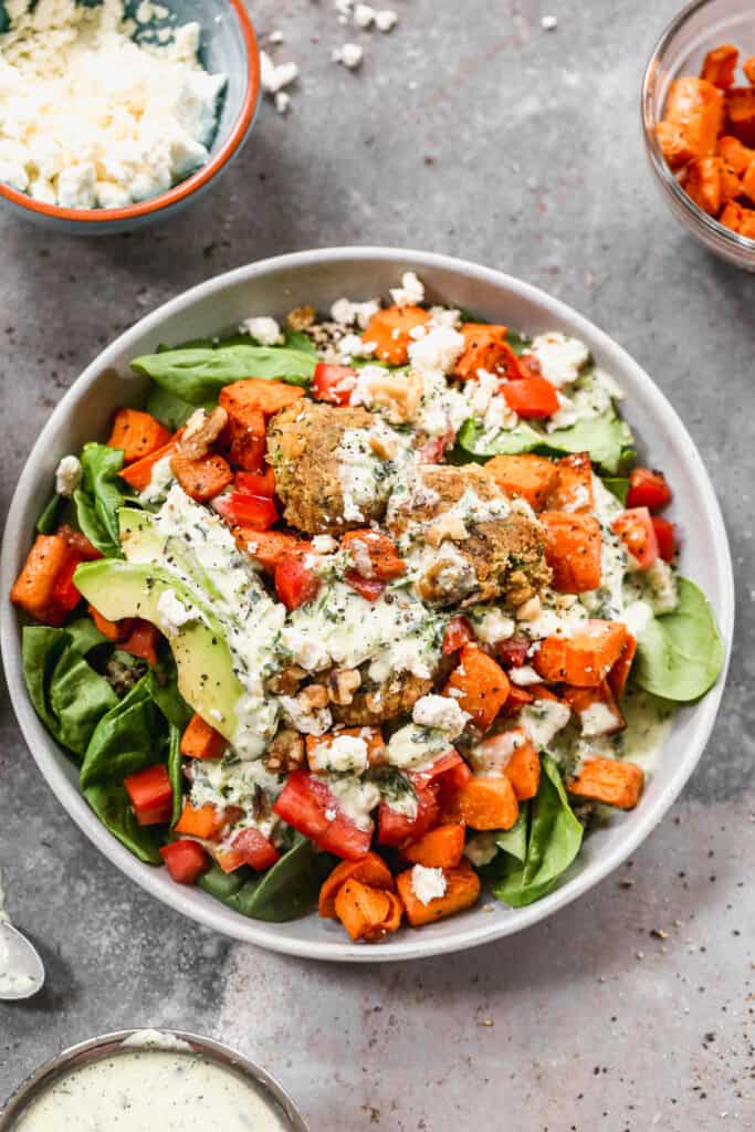 A homemade Buddha Bowl recipe with grains, roasted vegetables, falafel, and topped with a jalapeño ranch dressing.